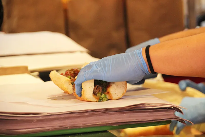 Philadelphia Italian roast pork sandwich from DiNic's in Reading Terminal Market with provolone cheese and broccoli rabe on a sesame seeded bun being assembled by a staff member